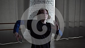 A girl in a black t-shirt, a master of modern dance performs in the studio of vogue, contemporary or hip hop