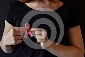 A girl in a black t-shirt with a pink ribbon on her chest is fighting cancer. Breast cancer awareness month. The concept of breast