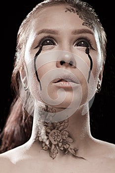 Girl with black tears from eyes and lace pattern on face and neck
