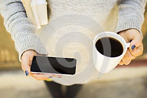 Girl with blank cell phone, cup of coffee and books