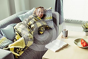 Girl in blanket relaxing on couch in living room