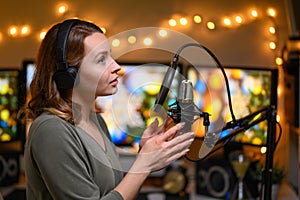 Girl blogger or radio host, working with a microphone, reading podcasts or news on the air. Homely and cozy atmosphere, work at