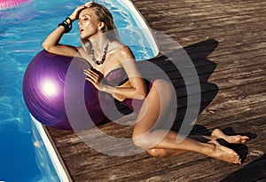 girl with blond hair in bikini beside a swimming pool