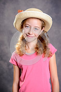 Girl with blond hair in pink shirt and straw hat