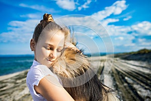 Girl with blond hair with smile hugs pomeranian dog with golden hair on seashore near Black Sea