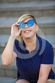 A girl with blond hair in sunglasses and blue t-shirt looking up