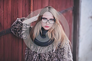 Girl blonde in cat eyes glasses in an artificial faux fur coat