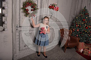 Girl blonde child with a pink teddy bear in hand with a Christmas wreath