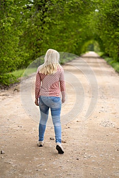 Girl blonde on the road somewhere going, tree arch