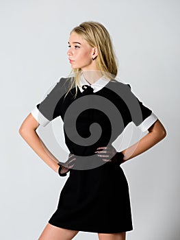 Girl blonde wear elegant black dress. Formal uniform elite school college or housemaid. Vintage model. Elegance in