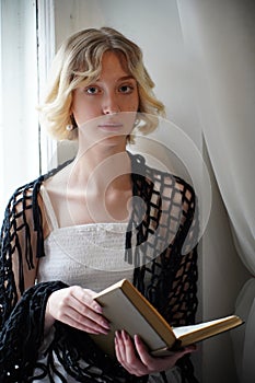 girl blonde at the window reads a book