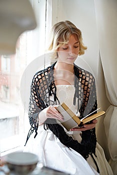 girl blonde at the window reads a book