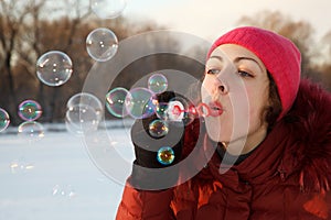 Girl blow bubbles in winter park.