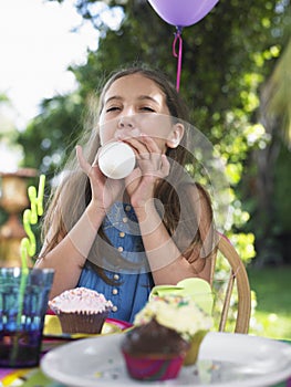 Girl Blowing Balloon At Birthday Party