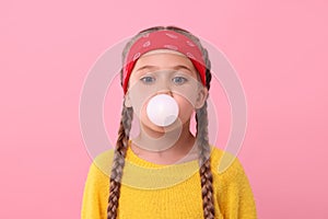 Girl blowing bubble gum on pink background