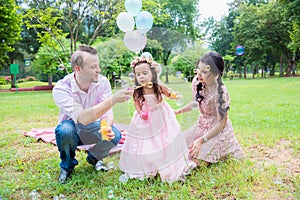 Girl blowing bubbles with her father and mother in park