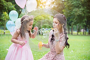 Girl blowing bubbles with her mother in park