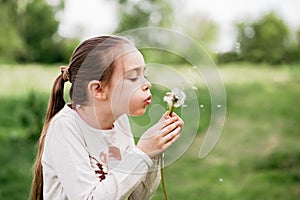 girl blowing dandelions flower selective focus. Allergy season