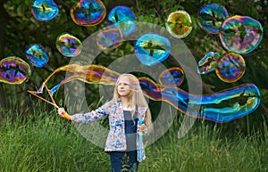 Girl blowing giant rainbow color soap bubbles