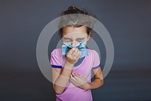 Girl blowing his nose into handkerchief on a gray