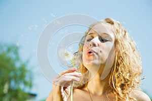 Girl blowing seeds of dandelion