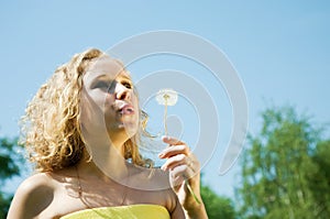 Girl blowing seeds of dandelion