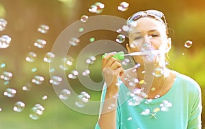 Girl blowing soap bubbles in sunlit park.