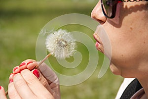 Girl blowing on white dandelion