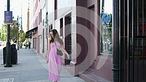 A girl blows a kiss as she passes by Canada Vancouver Wind blows smiling young woman In city center, young girl in pink