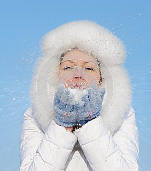 Girl blows off snowflakes from the hand