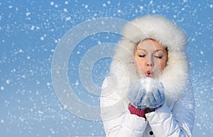 Girl blows off snowflakes from the hand