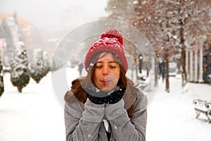 The girl blows off snowflakes from her hands