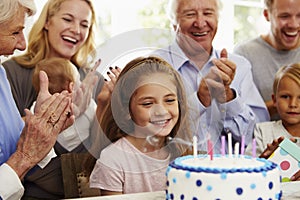 Girl Blows Out Birthday Cake Candles At Family Party