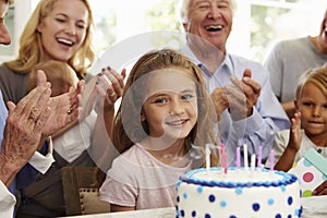 Girl Blows Out Birthday Cake Candles At Family Party