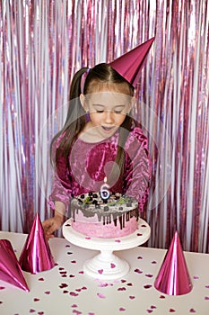 Girl blows out burning candle on cake making cherished wish on sixth birthday