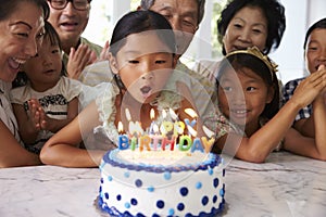 Girl Blows Out Candles At Family Birthday Celebration