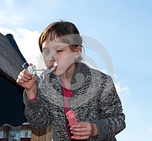 A girl blows soap bubbles against the sky. Children`s games and entertainment