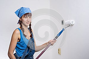 The girl in blue clothes pours paint roller white wall in the room.