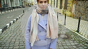 Girl in a blue coat posing at the camera, walking around the city