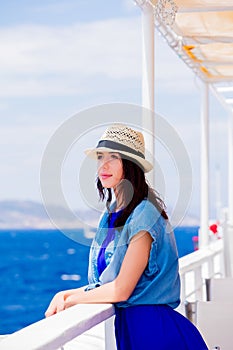 Girl in blue dress and hat have a voyage on a boat