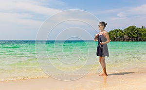 Girl listening to music on the beach holding smartphone