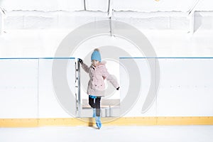 Girl in blue hat and pink jacket is going for ice skating