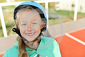 A girl in a blue helmet roller skates in the stadium