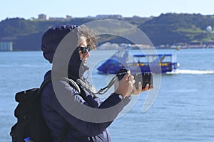 A girl in a blue jacket holds a camera in her hands