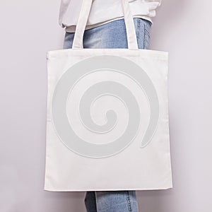 Girl in blue jeans holds blank cotton eco tote bag, design mockup. Handmade shopping bag for girls photo