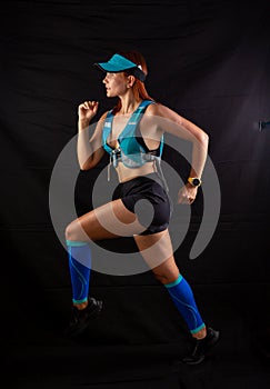 Girl in blue jogging uniform runs in the studio on a black background