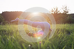 a girl in blue leggings does a stretching throwing her legs over herself lying in a park in the fresh air lying on a rug