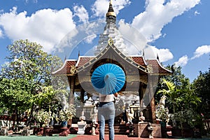 Girl with a blue umbrella in front of a Buddhist temple