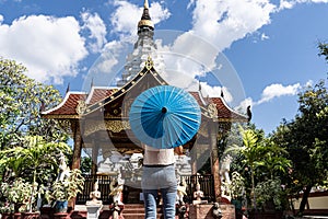 Girl with a blue umbrella in front of a Buddhist temple