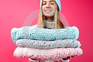 The girl in the blue warm hat, holding scarves on a red background.